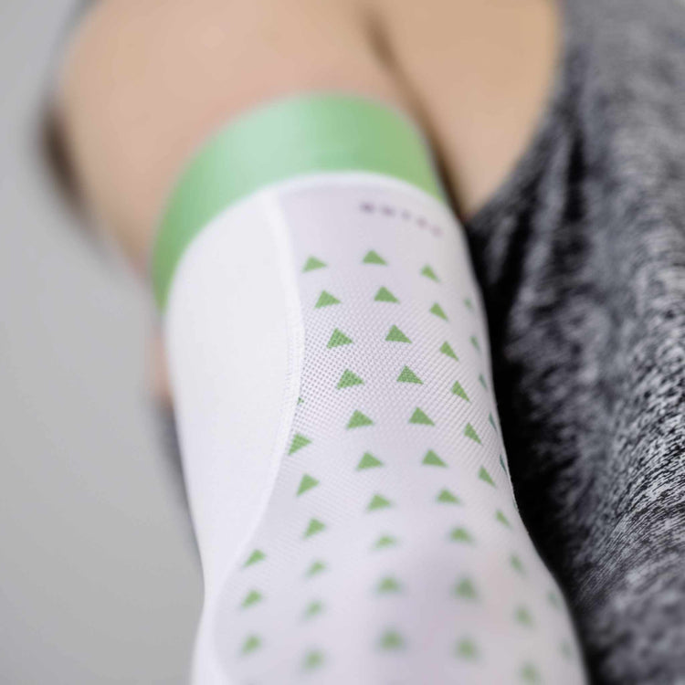 Close-up of a white arm sleeve with mint green details, featuring a sleek, aerodynamic design for basket ballers, XC runners and more.