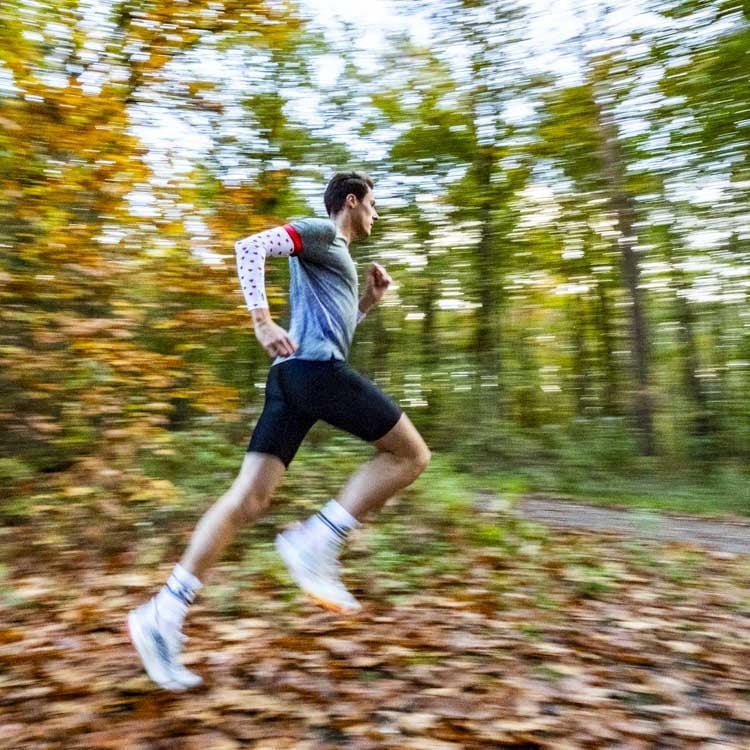 Arm sleeves protect cross country runners from cold conditions while running in the forest.